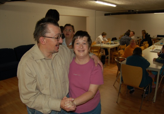Mann lächelnd hält Frau ebenfalls lächelnd im Arm und sie tanzen miteinander