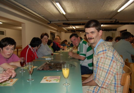 Mehrere Leute sitzen gemeinsam bei einem langen Tisch mit Getränken