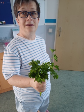 Eine Frau mit Brille hält eine kleinen Strauß Petersilie in der Hand