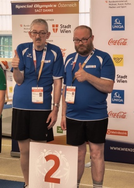 Zwei Sportler vor dem 2. Platz Schild