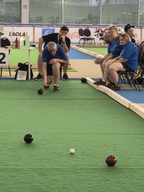 Mann auf einer Bocciabahn beim Spielen mit Zuschauern