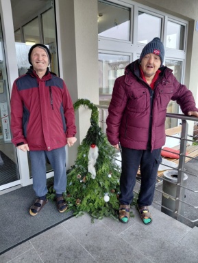 Zwei Männer stehen vor ihrem selbstgebastelten Wichtel aus Tannenzweigen