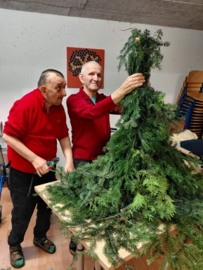 Zwei Männer basteln einen Wichtel aus Tannenzweigen