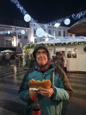Ein Mann am Weihnachtsmarkt mit einem Langos in der Hand