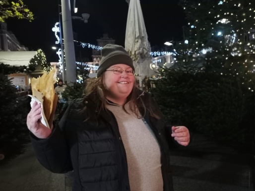 Eine Frau am Weihnachtsmarkt mit einem Langos in der Hand