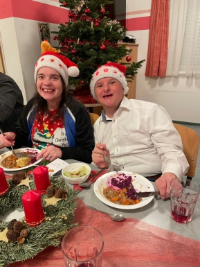 Mann und Frau mit Weihnachtsm&uuml;tzen beim Essen