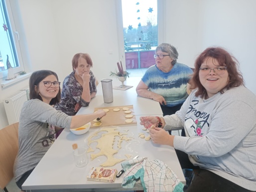 Frauen sitzen beim Tisch und backen gemeinsam